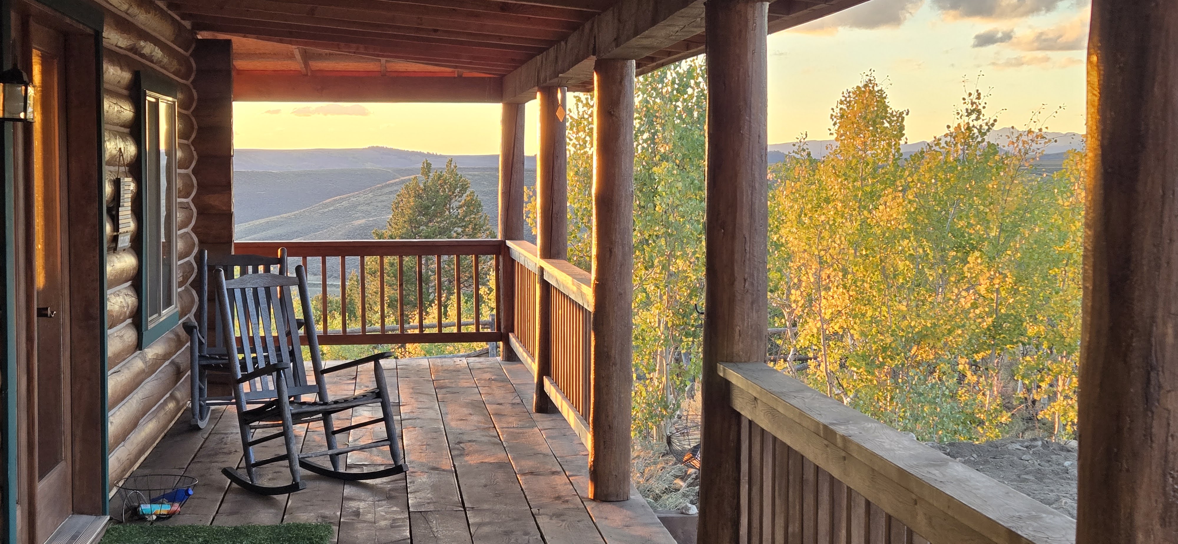 Wrap-around porch with rocking chair overlooking autumn hills at golden hour