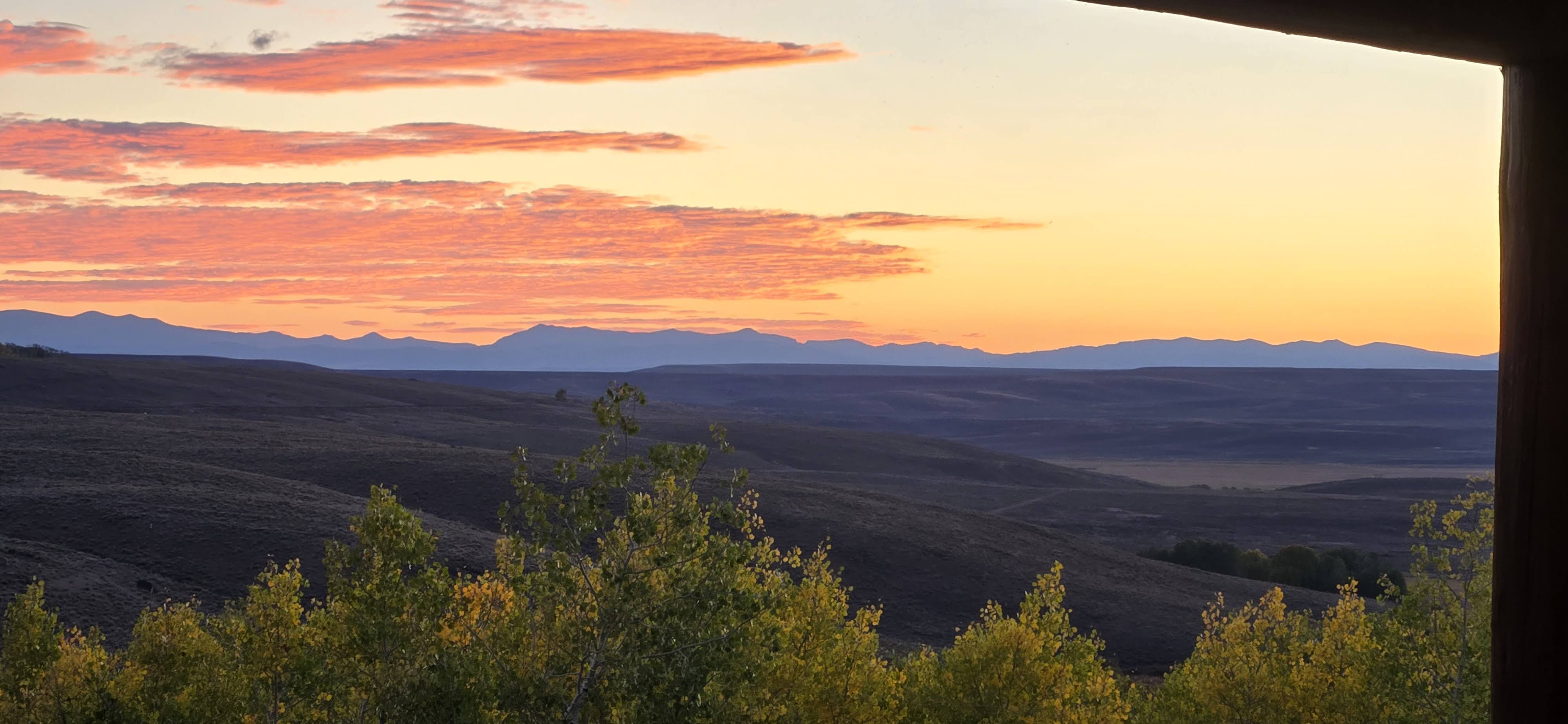 Golden-hour sunset view from the cabin porch — peaceful mountain sky